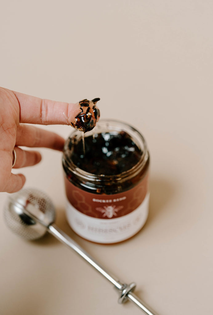 Finger dipped in Rockee Redd Hibiscus honey jar with tea infuser